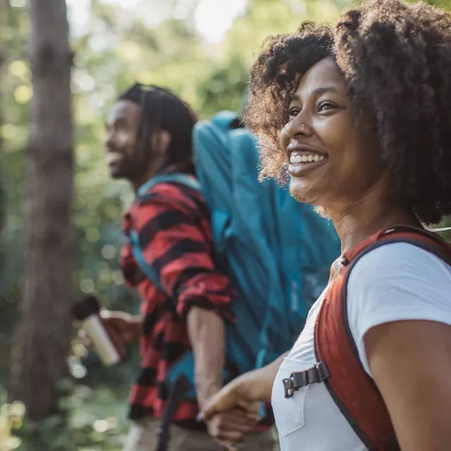 Couple hiking through forest while holding hands