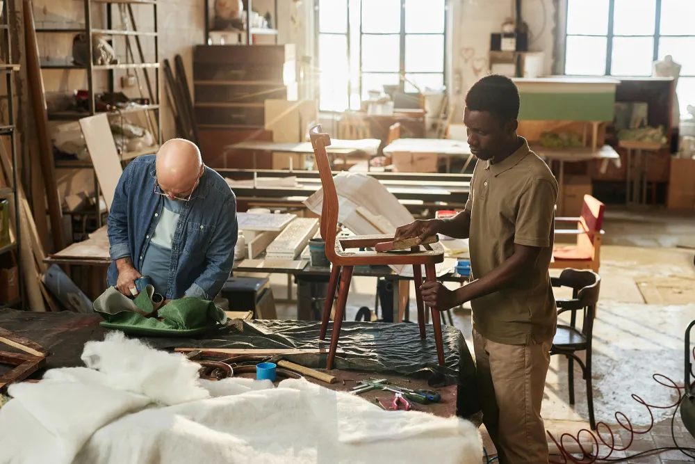 two people working on a chair made from wood