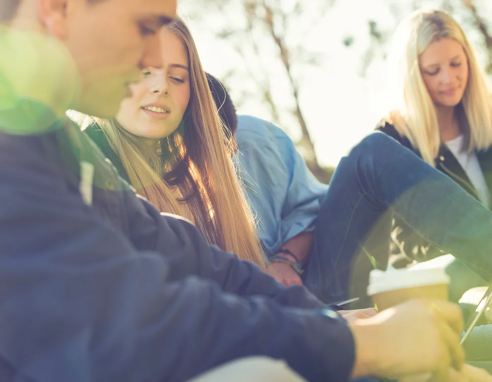 high school students studying outside under shade trees