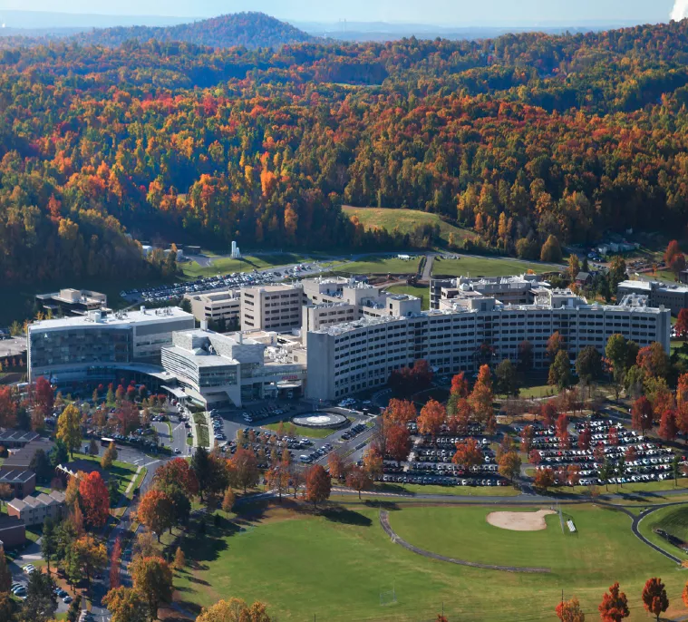 Overhead view of Penn State Health campus buildings in autumn, featuring fall foliage and clear blue sky.