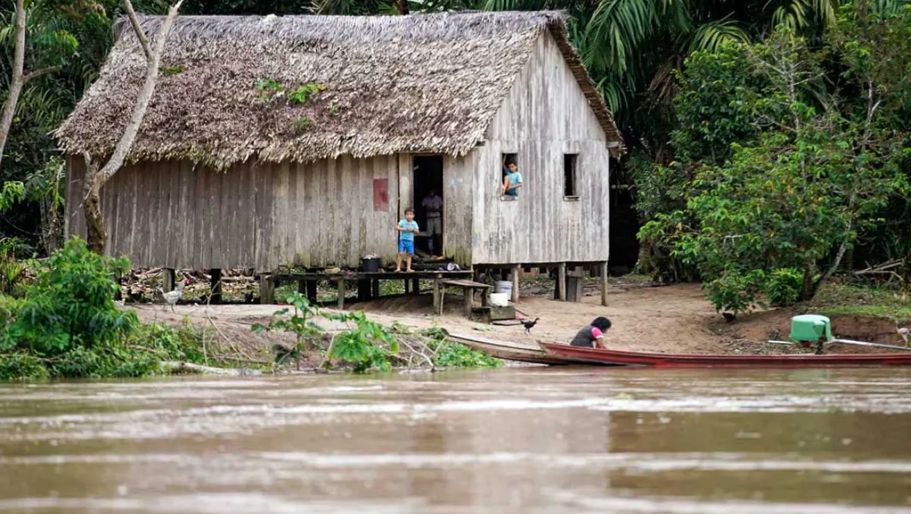 Kids next to hut and river in Amazon Rain Forest