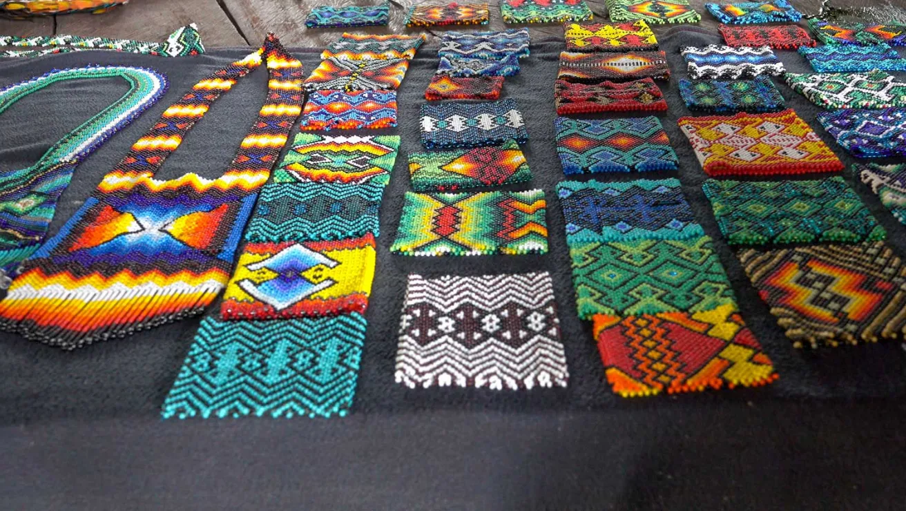 A colorful table showcasing a variety of beaded art pieces.