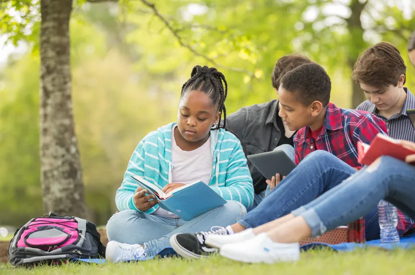 group of middle school students sitting under a tree and talking