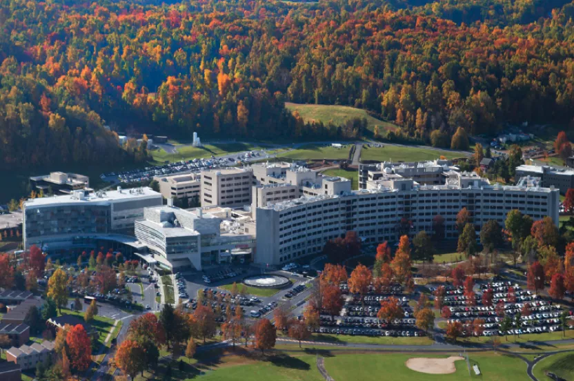 Overhead view of Penn State Health campus buildings in autumn, featuring fall foliage and clear blue sky.