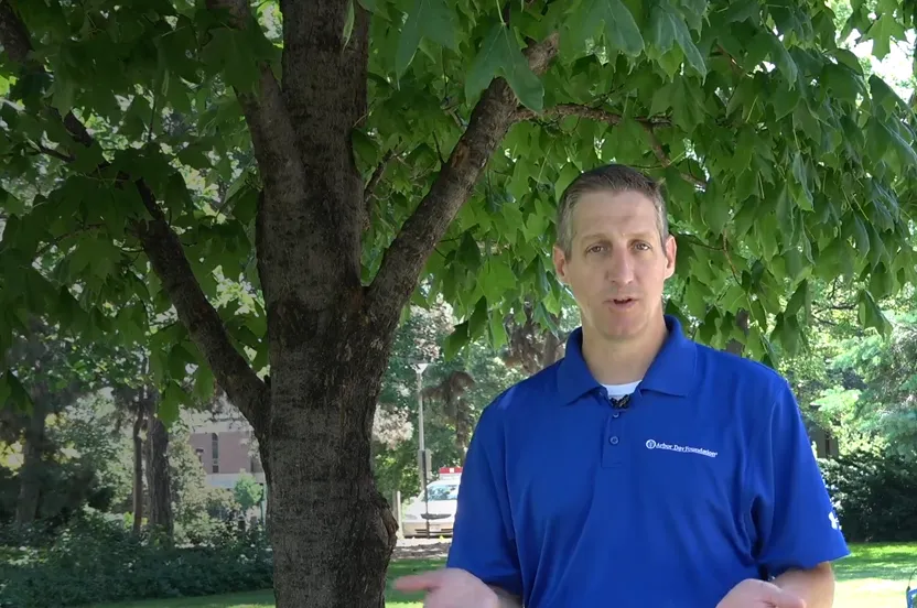 Man talking to camera in front of a tree.